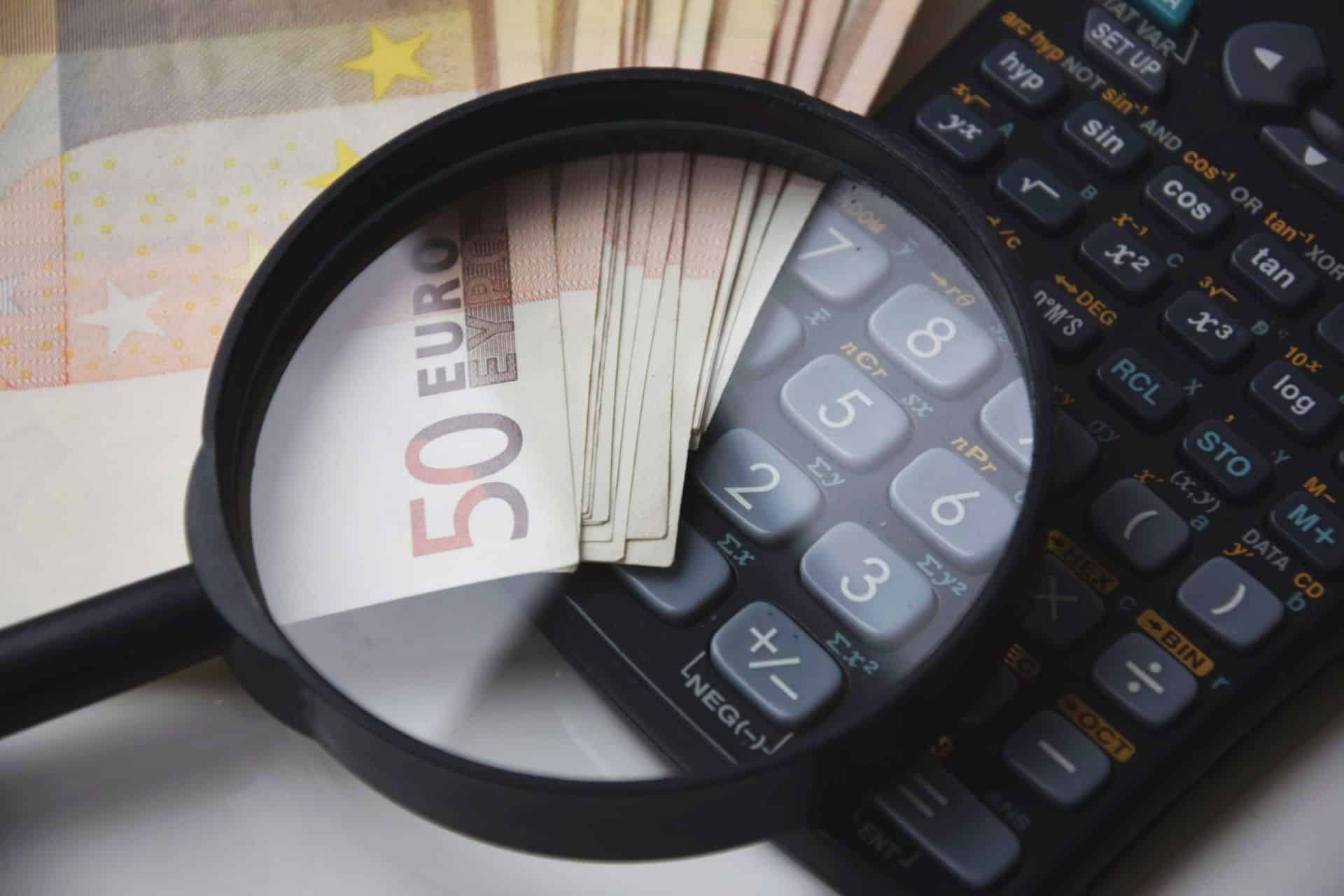 Magnifying glass over euro notes and a calculator